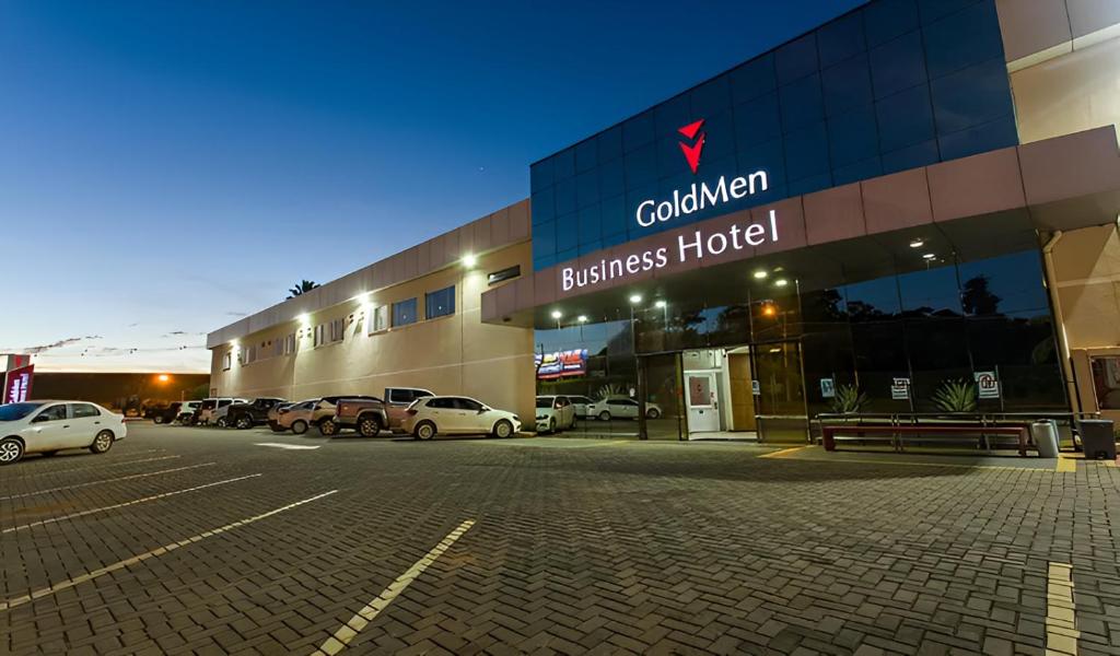 a building with cars parked in a parking lot at Goldmen Business Hotel in Cianorte