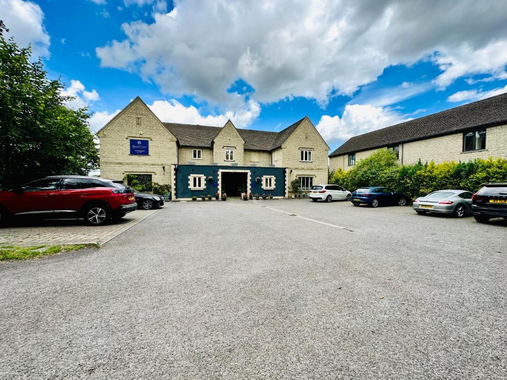 una casa grande con coches aparcados en un aparcamiento en The Churchill Court en Woodstock