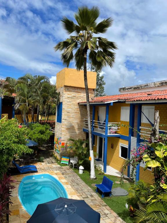 a house with a palm tree and a swimming pool at Pousada Girassol in Porto De Galinhas