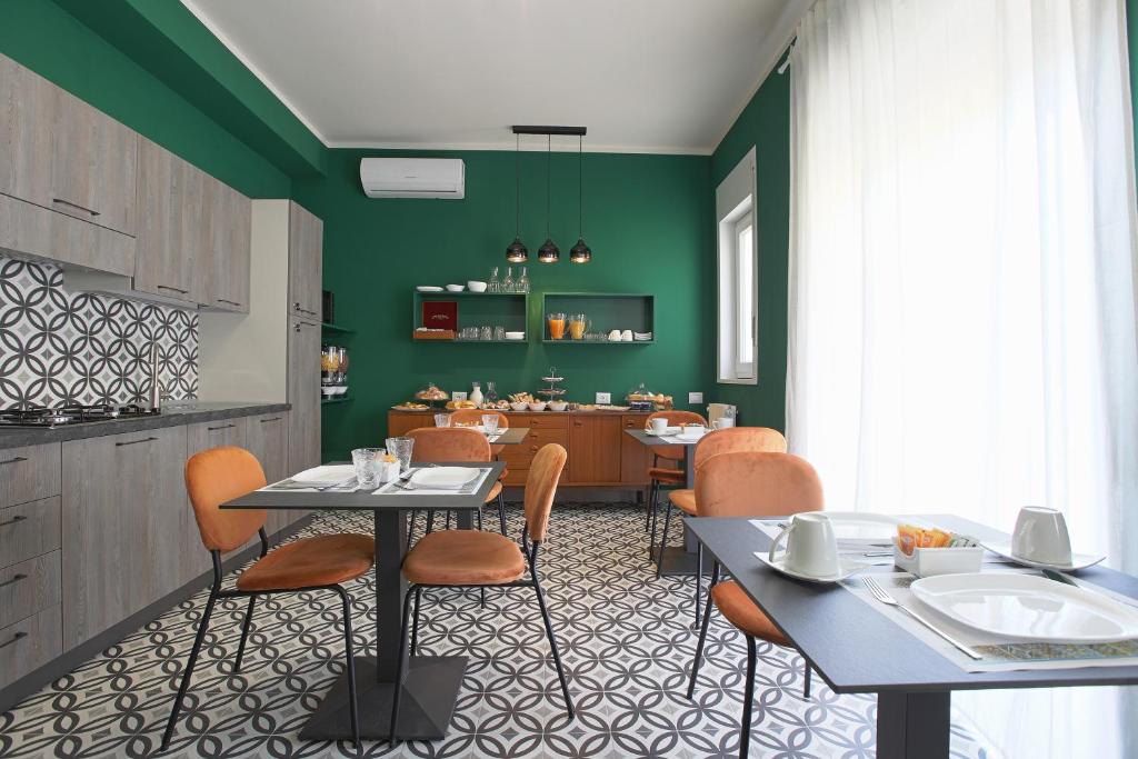 un comedor con paredes verdes, mesas y sillas en Malù - Bed &amp; Breakfast, en Agrigento