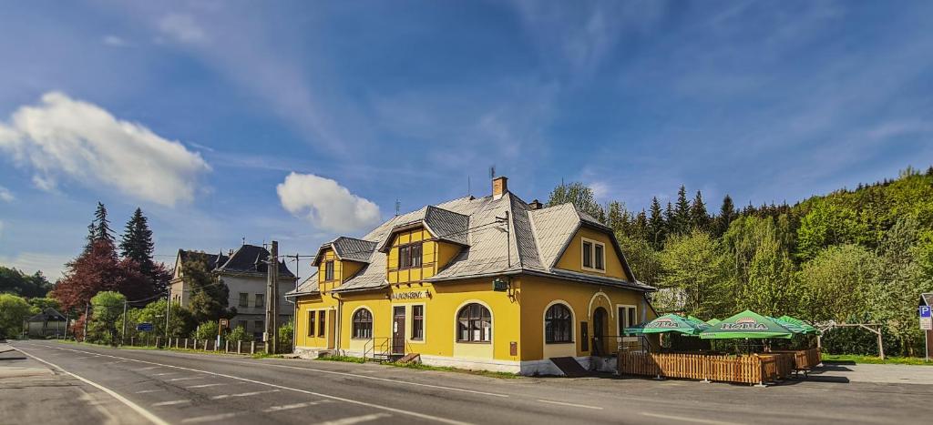 una casa amarilla sentada al lado de una calle en Penzion U Kovárny, en Malá Morávka