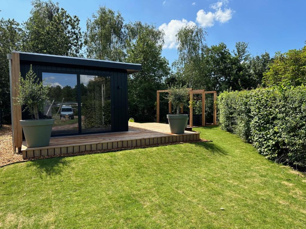 a modern shed with a deck in a garden at Chalet de Blauwe regen in Balkbrug