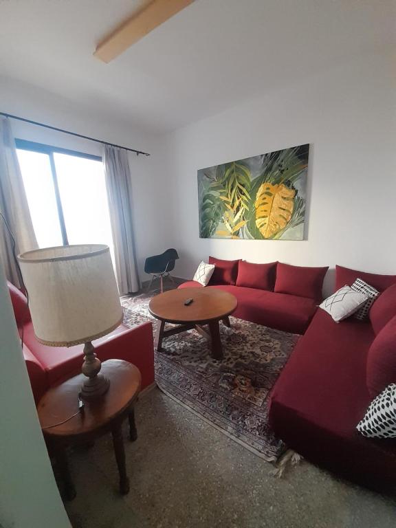 a living room with a red couch and a table at Résidence artistique Vue sur mer in Larache