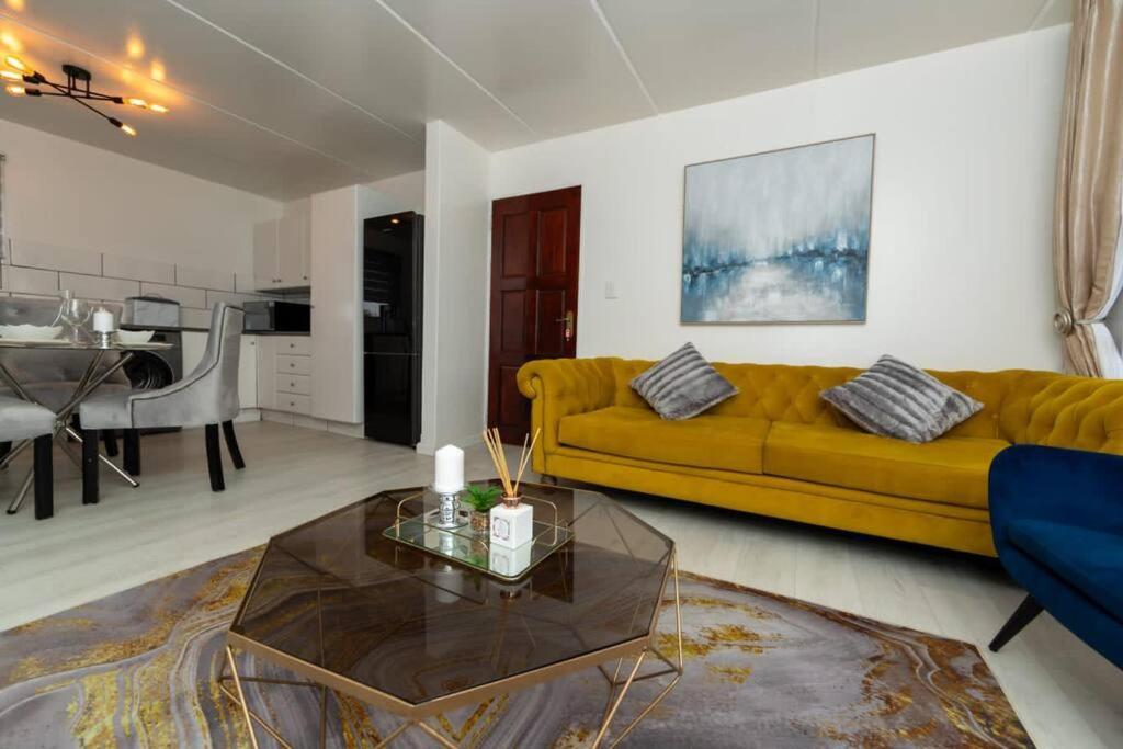 a living room with a yellow couch and a table at Havens corner in Sandton