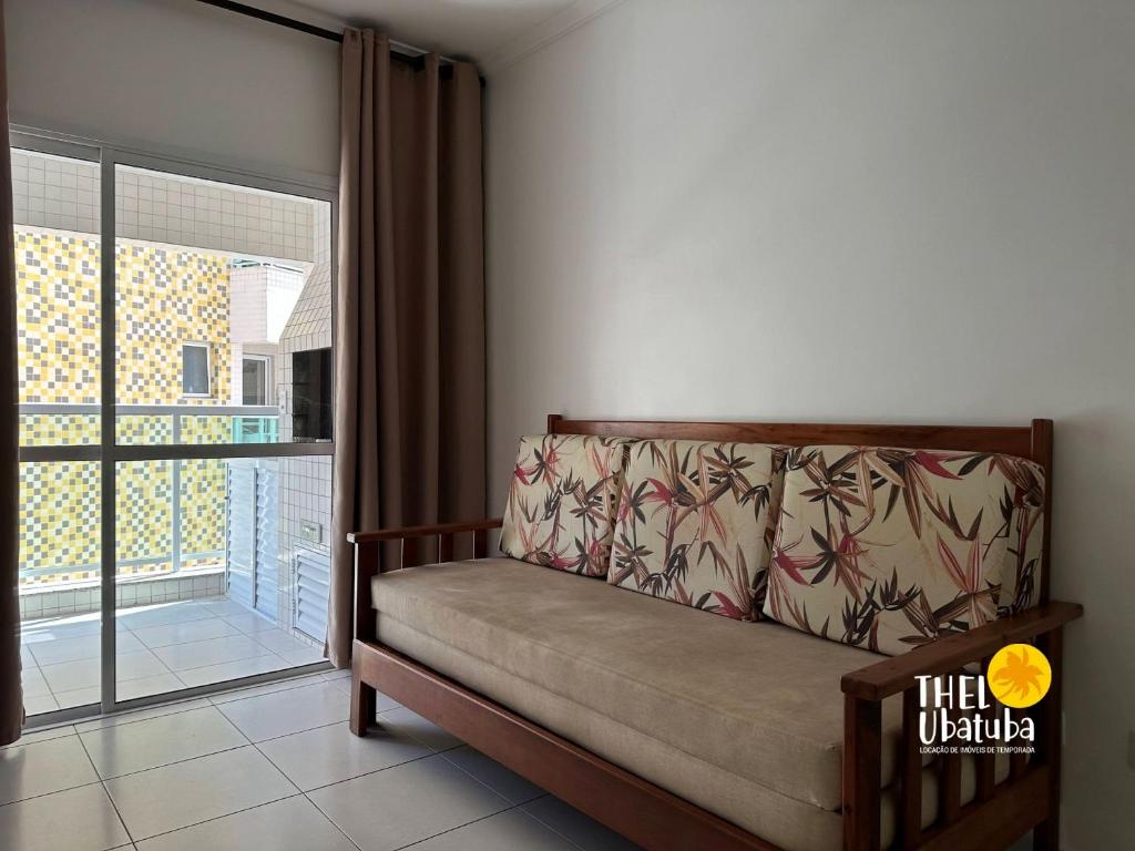 a couch in a room with a large window at Thel Ubatuba - Apto 27/A, Monte Carlo - Praia Grande in Ubatuba