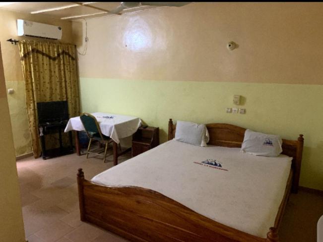 1 dormitorio con cama de madera, mesa y mesa en Hôtel cœur des montagnes en Abomey