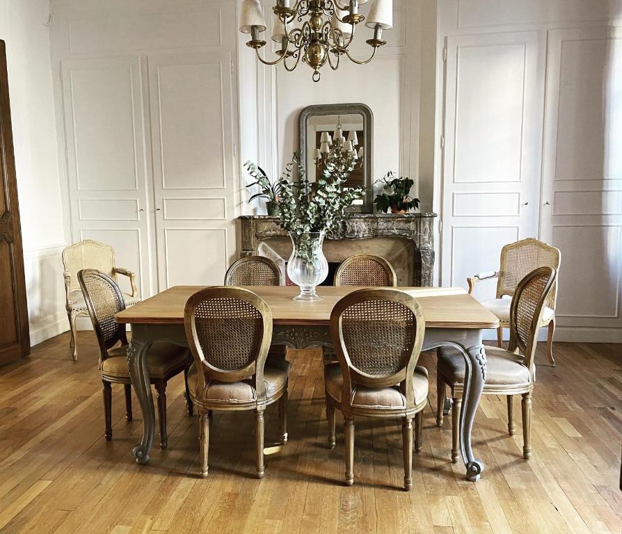 een eettafel met stoelen en een vaas met bloemen bij Hôtel particulier Champenois in Châlons-en-Champagne