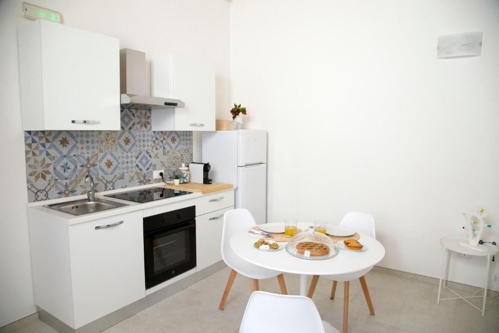 a white kitchen with a white table and chairs at Casa Sole in Lecce