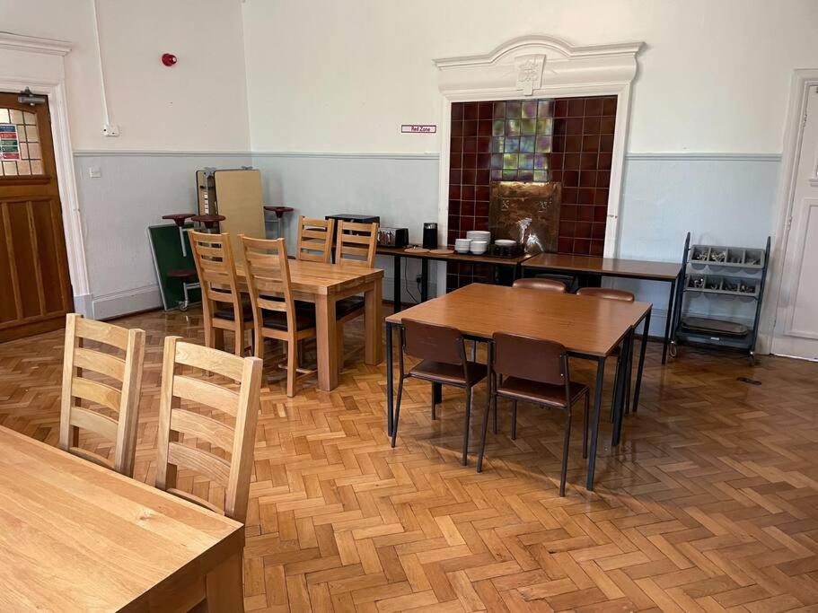 a dining room with wooden tables and chairs at Marle Hall - Dorm Rooms (Yellow) in Llandudno Junction