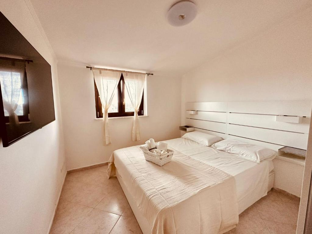 ein weißes Schlafzimmer mit einem Bett und einem Korb darauf in der Unterkunft La Ginestra Ciampino in Ciampino