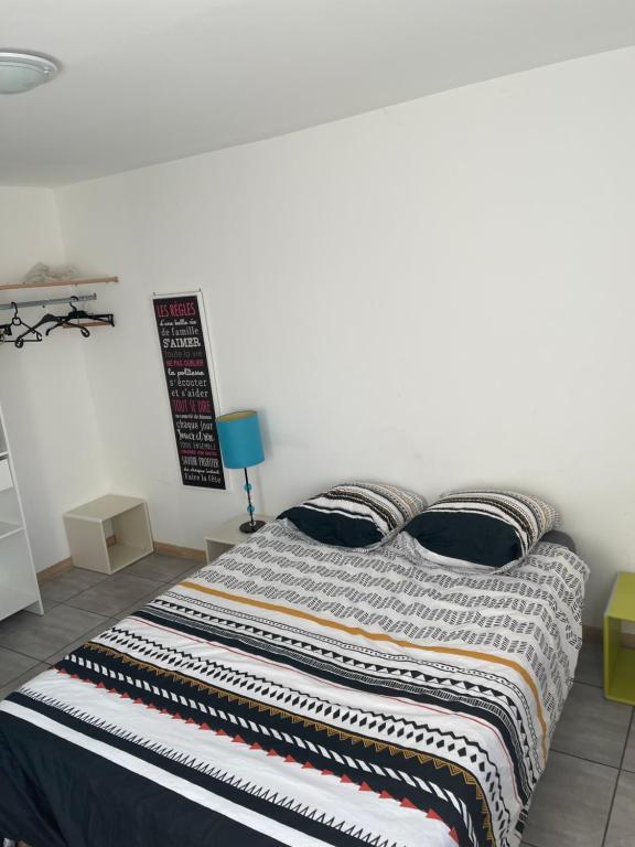 łóżko z kołdrą w paskach w pokoju w obiekcie Petite maison avec 2 chambres 