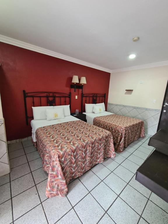 2 camas en una habitación de hotel con paredes rojas en Hotel TorreBlanca, en Culiacán