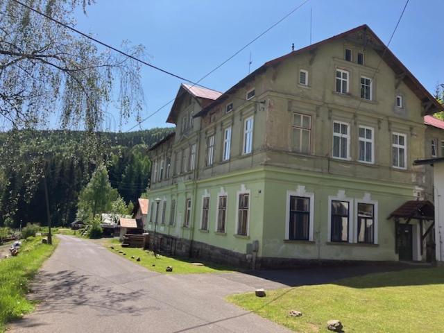 ein großes, grünes Gebäude mit einer Straße davor in der Unterkunft Kořenov byt Alda in Kořenov