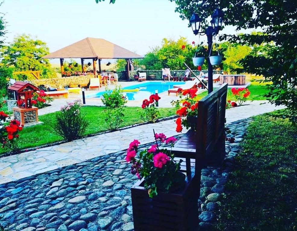 einen Garten mit einer Bank mit Blumen und einem Pool in der Unterkunft Krcma u Planini 