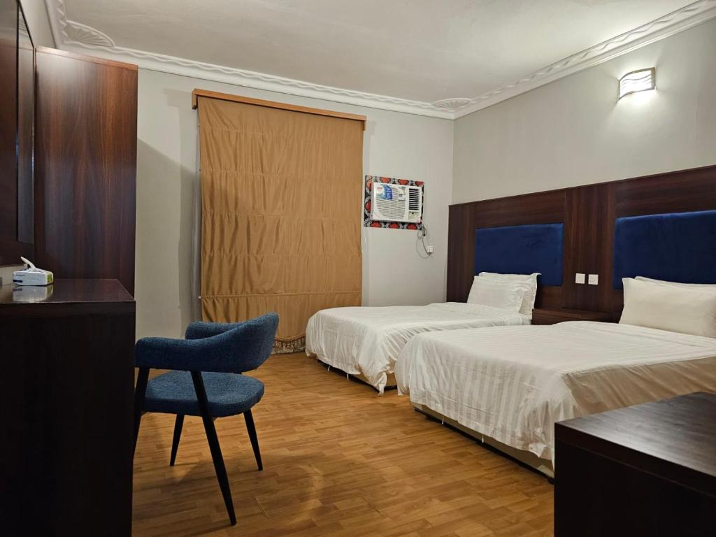 una habitación de hotel con 2 camas y una silla en Safa PARK HOTEL YANBU فندق صفا بارك ينبع, en Yanbu