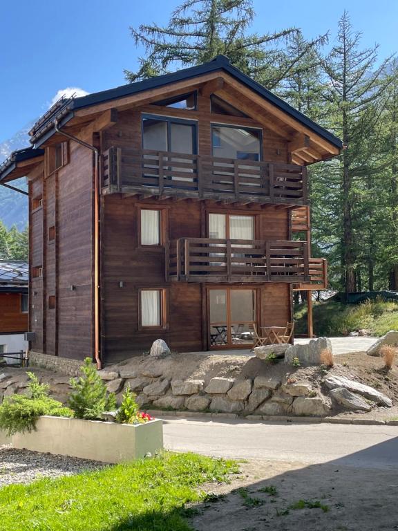 Cette grande maison en bois possède un grand balcon. dans l'établissement Chalet Tannegg, à Saas-Fee