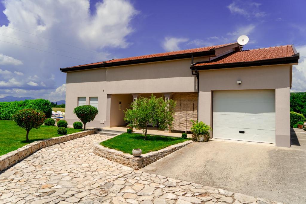 a house with a driveway and a garage at Villa KOD BUBE in Ljubuški