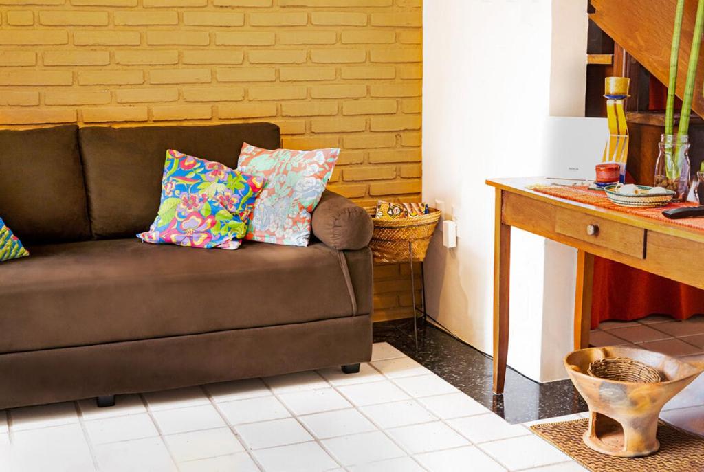 um sofá castanho com almofadas numa sala de estar em Apartamento a 400 metros da Praia do Frances-AL em Marechal Deodoro