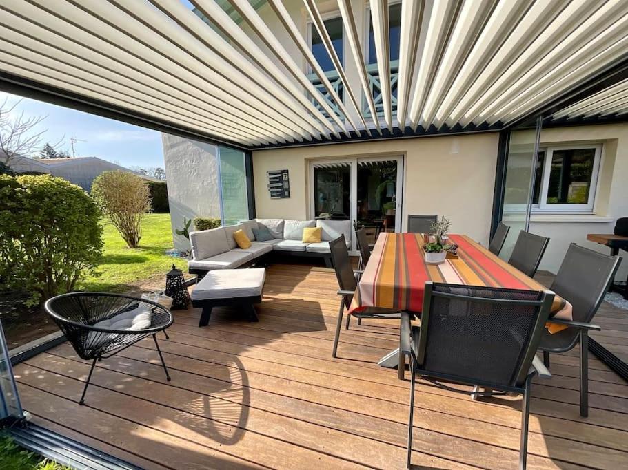 een terras met een tafel en stoelen en een bank bij La Villa Louca in Saint-Vincent-de-Tyrosse