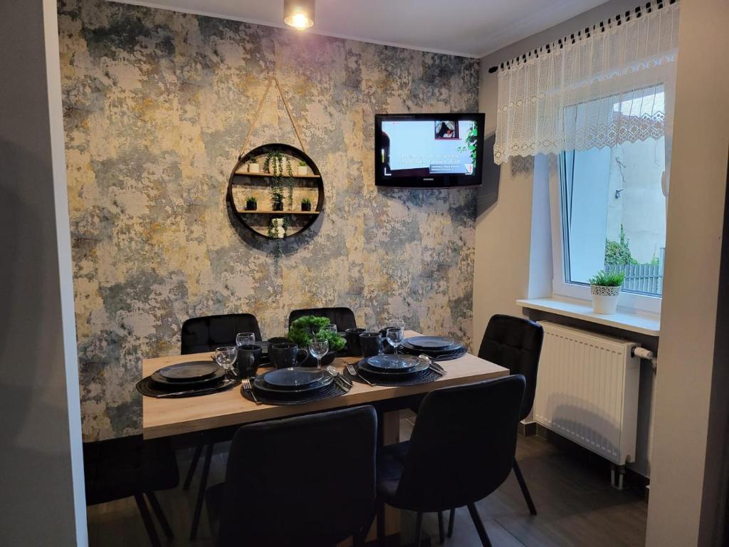 een eettafel met stoelen en een televisie aan de muur bij Apartamenty Premium Biznes Rumia in Rumia