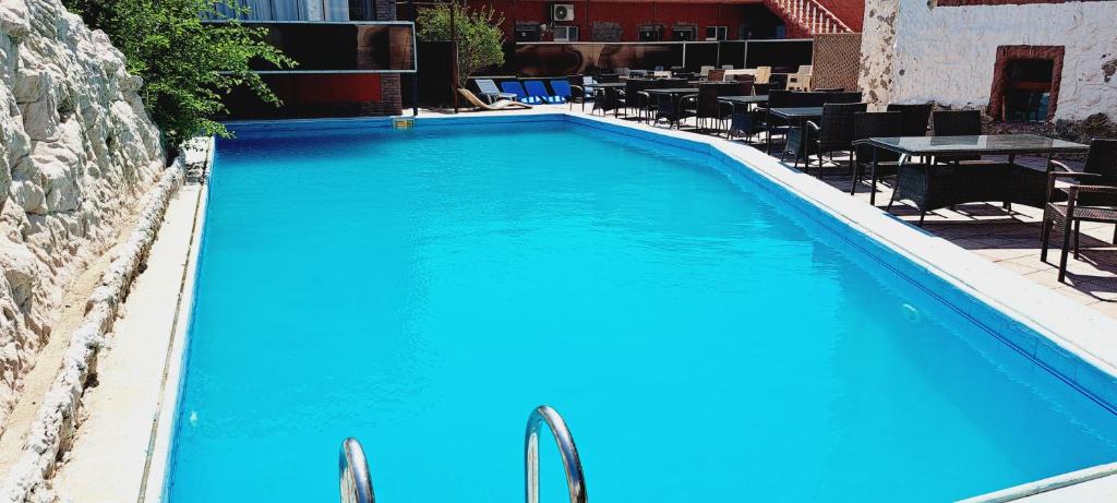 uma grande piscina azul com mesas e cadeiras em Mardin Hotel Novxanı em Baku
