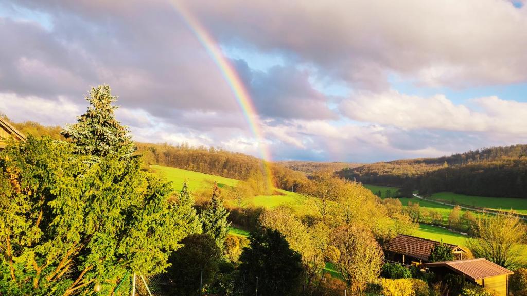 un arco iris en el cielo sobre un campo con árboles en romantische Ferienwohnung im Vogelsbergkreis, 