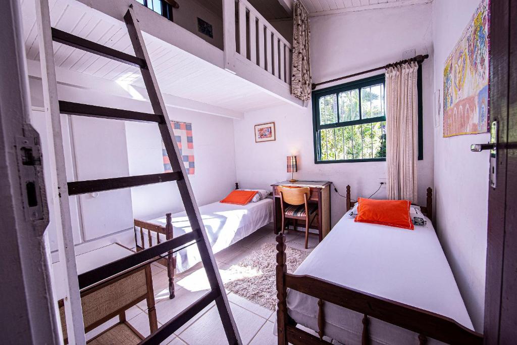a bedroom with two bunk beds and a ladder at Casa com Piscina a 100 m. de Camburizinho in Camburi