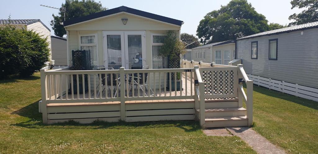 a small house with a porch and a fence at 2 bed pet friendly caravan at Hoburne Devon Bay with decking in Paignton
