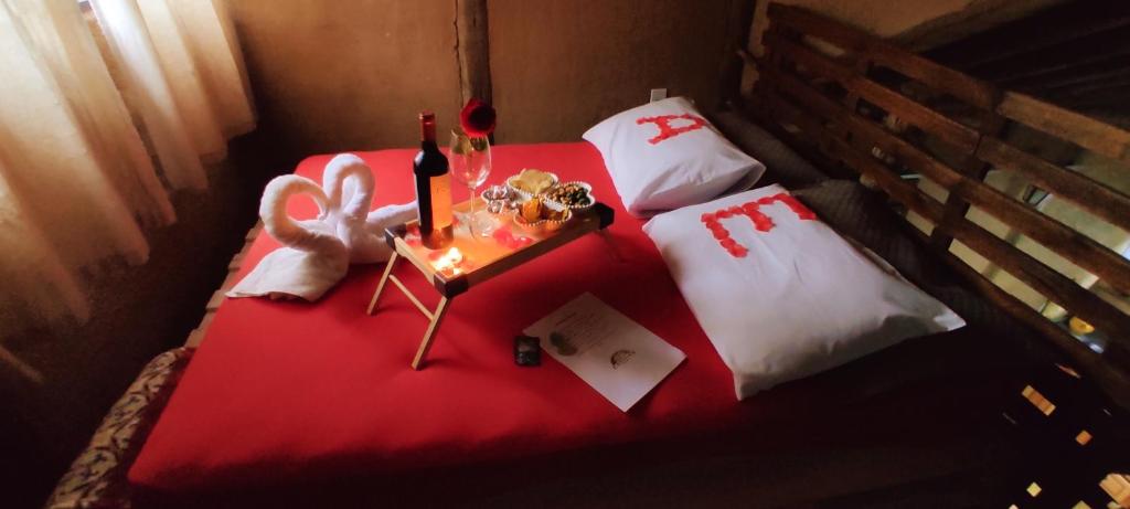 2 camas individuais com lençóis vermelhos e uma mesa com velas em Cabana Africana em Imaruí