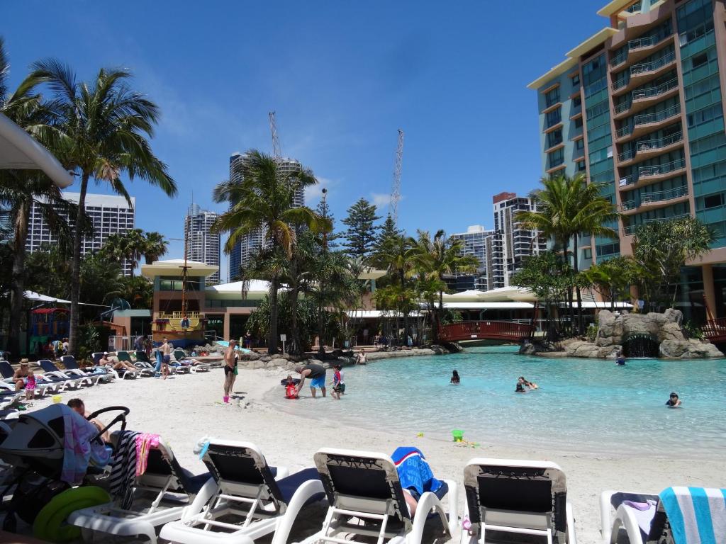 a beach with chairs and people in a swimming pool at Crown Towers in Gold Coast