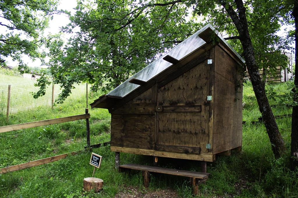 a wooden outhouse sitting in the grass next to a tree at BorgoGuerzano77 in Camugnano