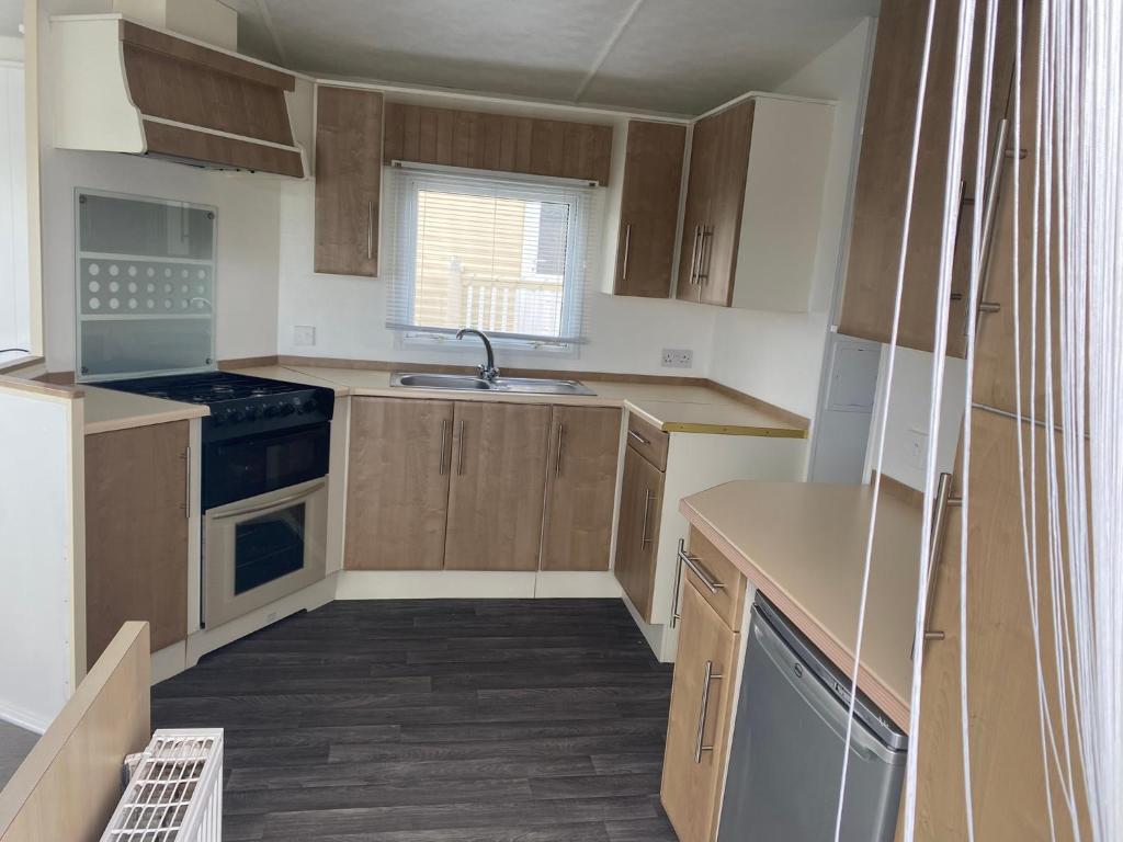 a small kitchen with wooden cabinets and a sink at ChaletAway in Leysdown-on-Sea