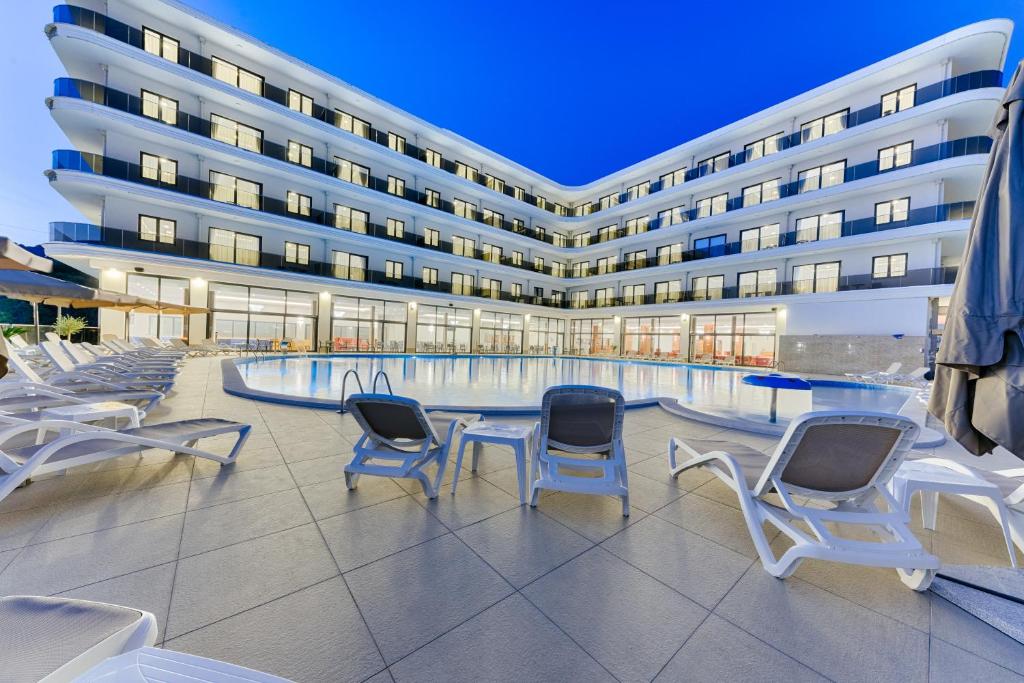 uma piscina de hotel com cadeiras e um edifício em Hotel BH em Dobra Voda