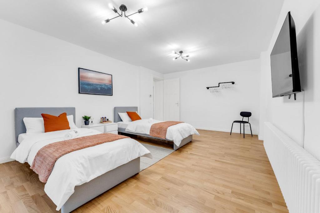 two beds in a bedroom with white walls and wood floors at 2 Zimmer Apartment,4 Betten am Sbahnhof Köpenick,vollmöbliert in Berlin