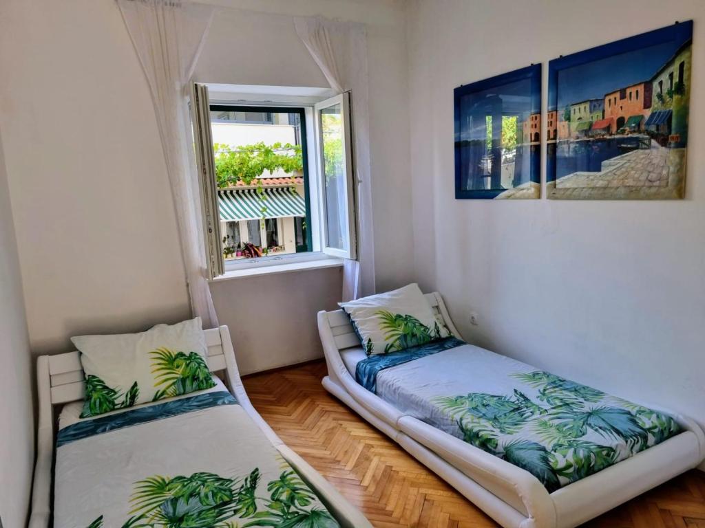 two beds in a room with a window at Glorianita sweethome,centro, FREE parking,SELF CHECK- IN in Šibenik