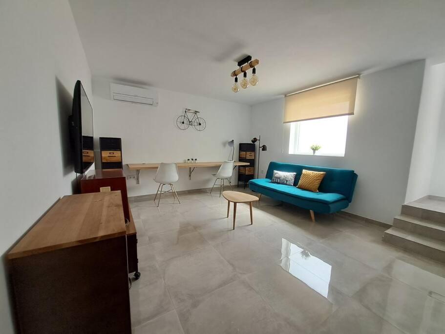 - un salon avec un canapé bleu et une table dans l'établissement Nueva Almería beach & chill, à Almería