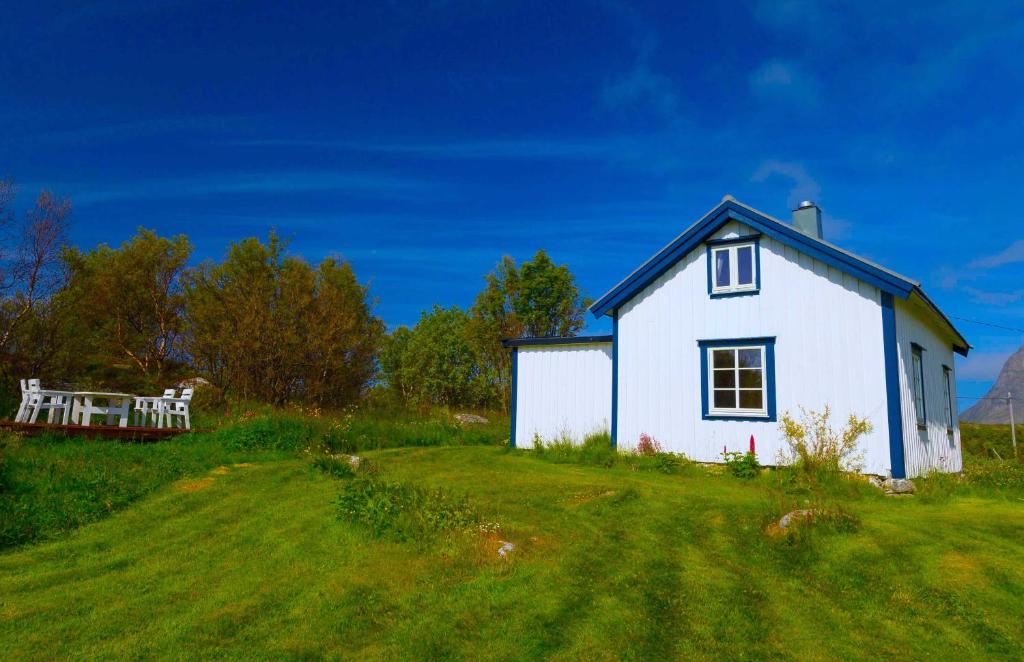 a small white house on a grassy hill with a bench at Cozy cabin with stunning view in Alstad