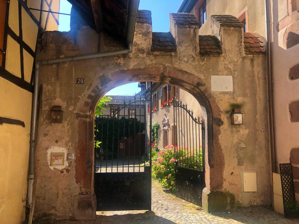 ein Torbogen, der zu einem Gebäude mit einem Tor führt in der Unterkunft Cour de Dinzheim in Riquewihr