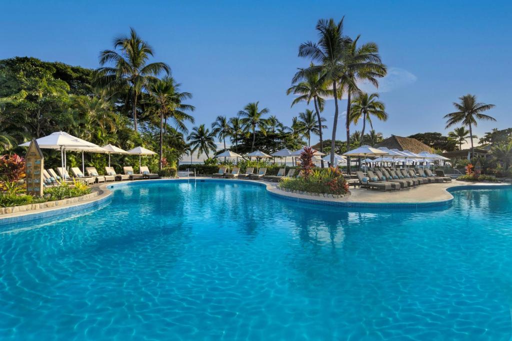a pool at a resort with palm trees and umbrellas at Sofitel Fiji Resort & Spa in Denarau