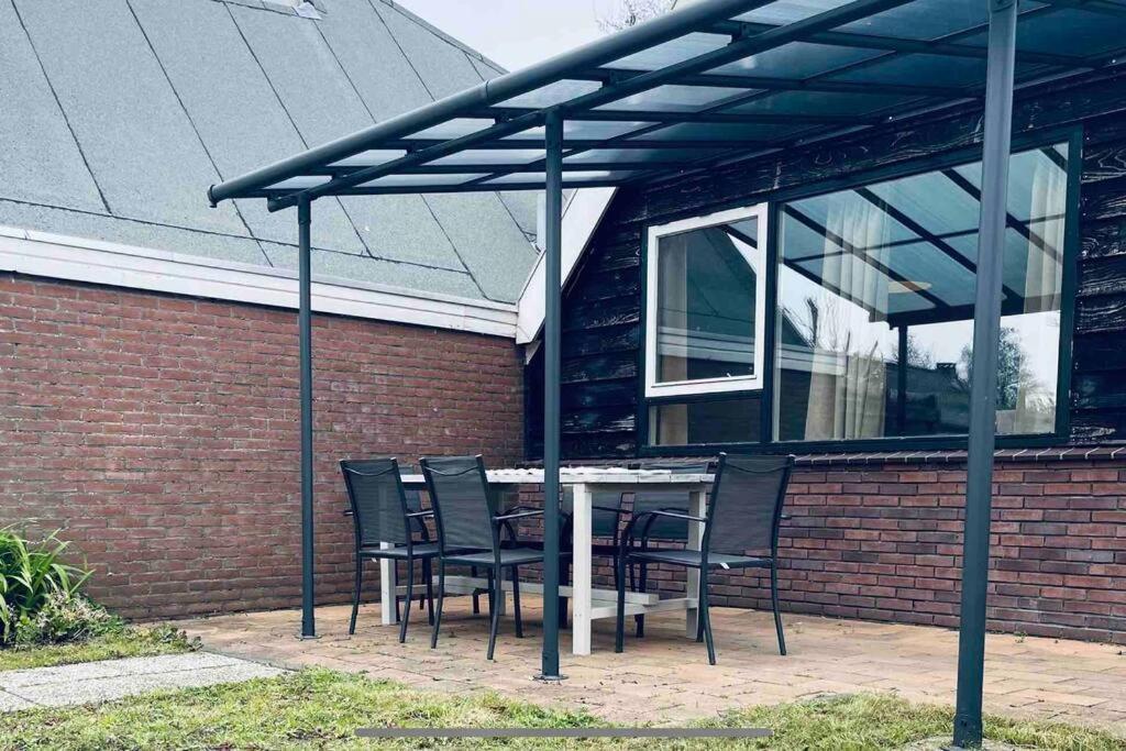 a table and chairs under awning outside of a building at Leuke bungalow in Noord-Holland in Opmeer