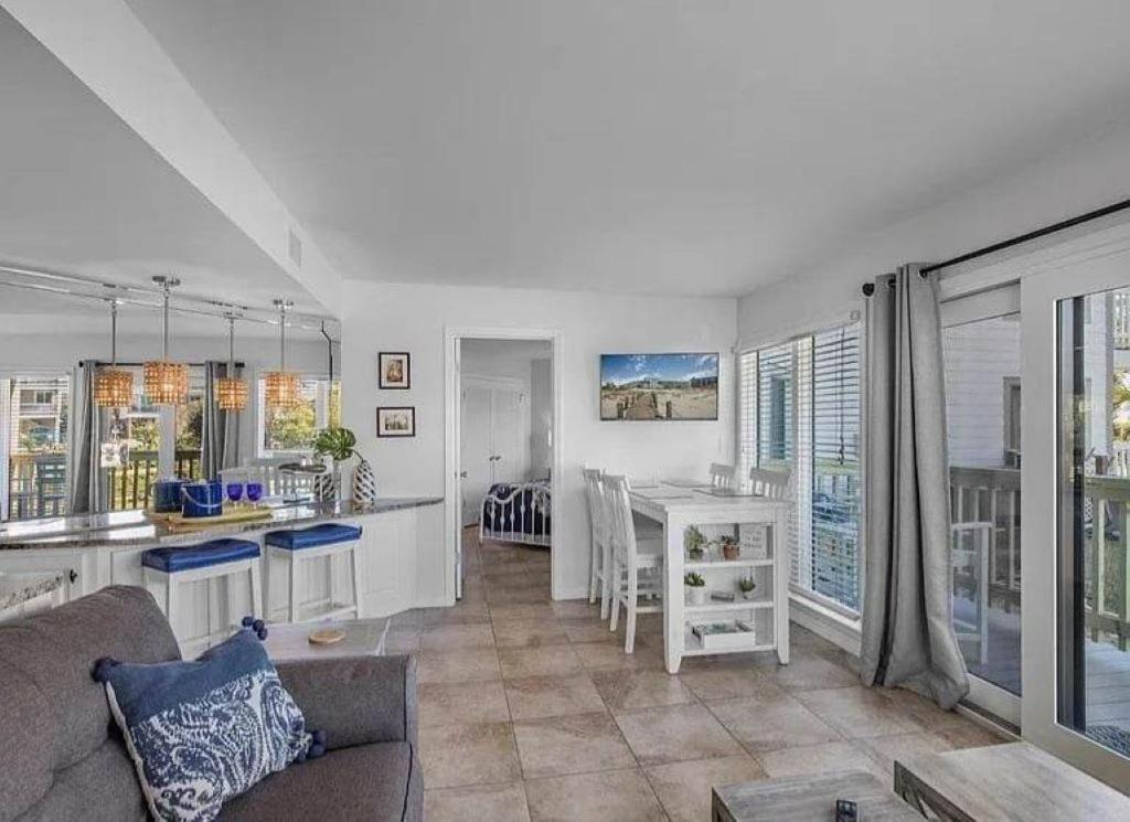 a living room with a couch and a kitchen with windows at Sugar Sands-Luxury 1st Floor 2BR 2BA Private Beach in Gulf Shores