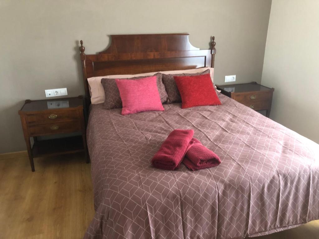 a bed with red and pink pillows on it at Casa Candelaria in Arguedas