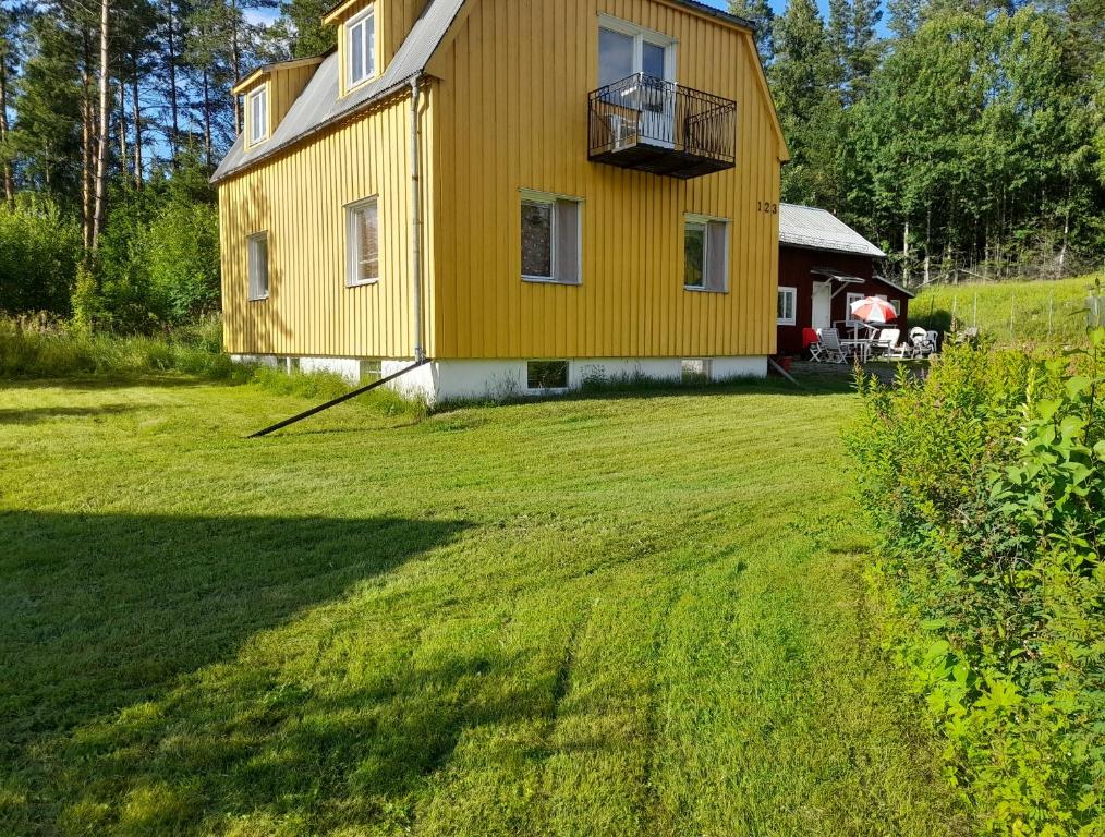 a yellow house with a balcony on a yard at Empty Lots in Camping near Sandbach in Bräcke