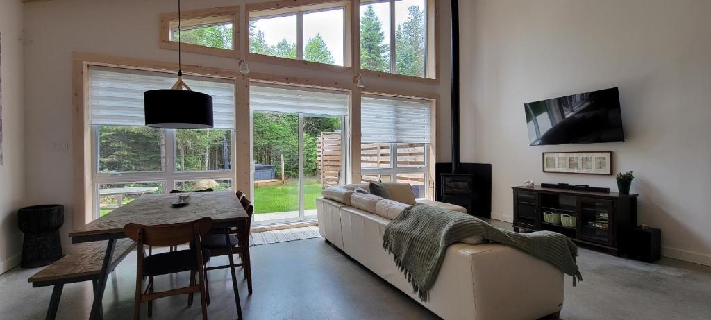 uma sala de estar com um sofá e uma mesa e janela em La Futaie em Saint-Donat-de-Montcalm