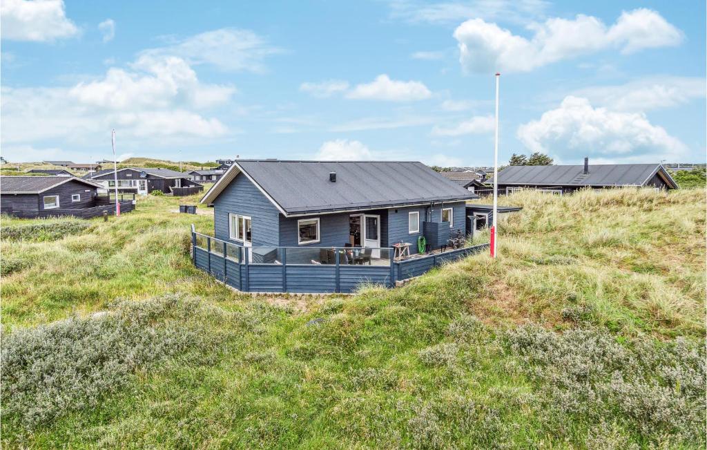 a blue house on top of a grassy hill at Lovely Home In Lkken With Kitchen in Løkken