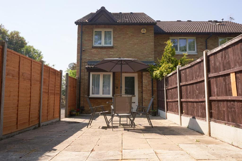 a patio with a table and an umbrella in front of a house at Superb One bedroom house in Thamesmead