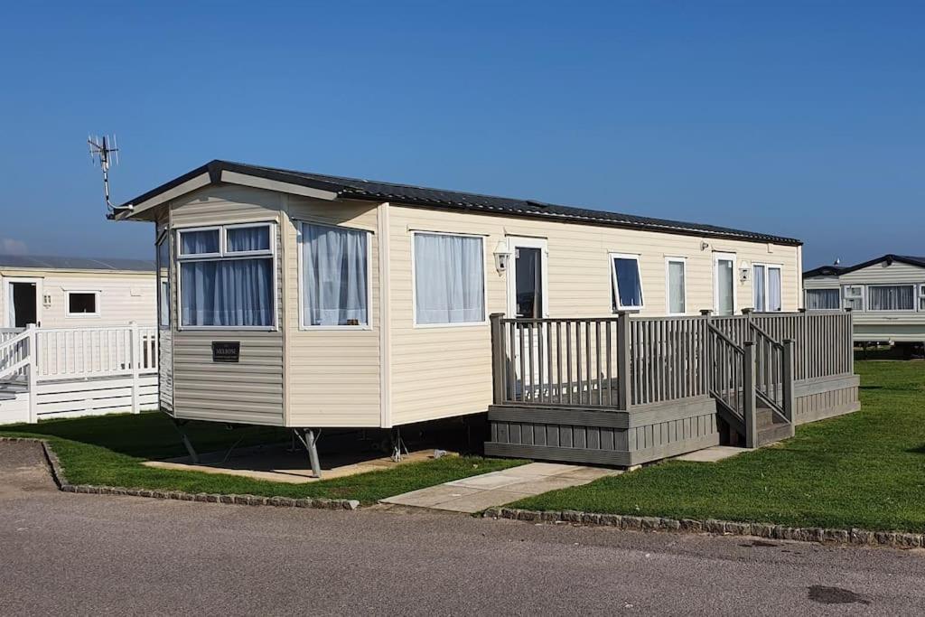 a small house with a fence in a yard at Carnaby Holiday Caravan, West Sands, Selsey in Selsey