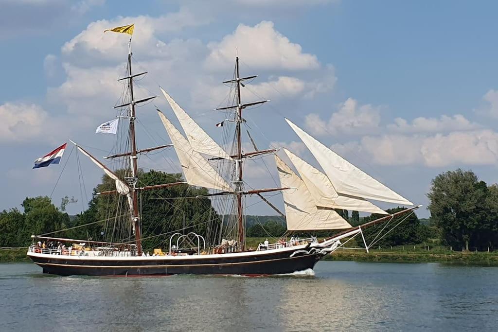 a large boat with white sails in the water at Location de maison Au fil de l O la Bouille in La Bouille