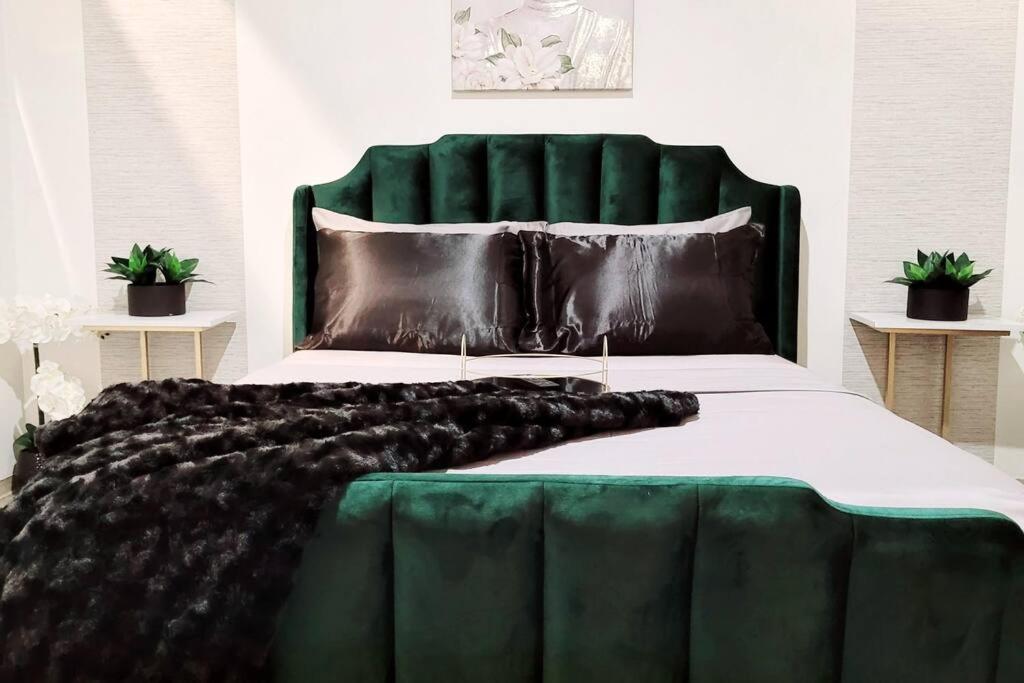 a large bed with a green headboard and black blanket at Staycation City Loft Free Gated Parking in Saint Louis