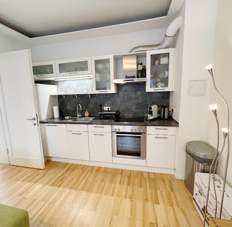 cocina con armarios blancos y suelo de madera en Prime Comfort Apartment with Balcony & Free Parking, en Berlín